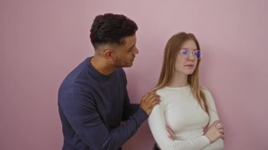 Bir çift, izole edilmiş pembe arka plana karşı kadınları rahatlatan bir erkekle ciddi bir konuşma yapıyor. Anlaşmazlık ve anlayış duygularını ifade ediyor..
