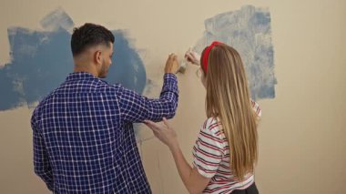 Yeni evdeki oturma odasında duvara kalp çizen genç çift kapalı alanda sevgi ve yaratıcılıklarını ifade ediyorlar.