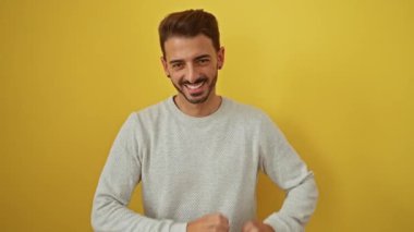 Genç İspanyol adam gülümsüyor. Sarı arka planda kalbi şekillendiriyor.