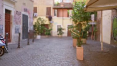 Roma 'daki bulanık sokak sahnesinde kaldırım taşları ve Akdeniz mimarisi ve yemyeşil verimli kentsel atmosfer yaratan eski kasaba cazibesi.