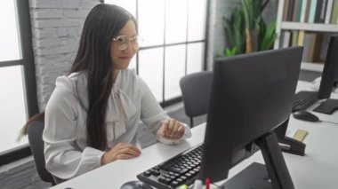 Ofiste gülümseyen bir kadın bilgisayarın yanında anahtarlarını tutuyor. Modern dekor ve teknolojiye sahip bir iş ortamında profesyonel başarı ve memnuniyet gösteriyor.