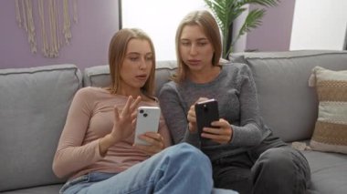 Rahat bir oturma odasındaki kanepede oturan kadın ikizler akıllı telefonlarla meşgul oluyor, aile bağlarını ve modern teknolojiyi samimi, rahat bir evde sergiliyorlar..