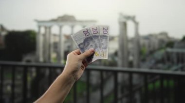 İsviçre Krona 'nın elinde Atina' daki antik harabelerin görüntüsüyle açık hava banknotları var. Bu da kültürel ve ekonomik değişim anlamına geliyor..