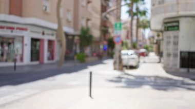 Bokeh efektli bulanık sokak sahnesi açık hava ortamını gösteriyor. Parlak, güneşli bir günde odakları kesilmiş arabalar ve vitrinlerle.