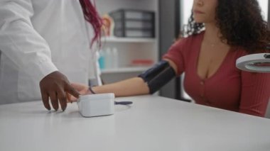Kadın doktor, modern bir klinikte kadın hastanın kan basıncını ölçüyor. Sağlık hizmetleri profesyonelliği ve hasta ilişkileri gösteriyor..