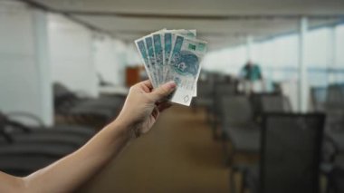 Tekne gezisi güvertesinde, arka planda bulanık heyecanı ifade eden, cilalı zloti paraları tutan bir adam..