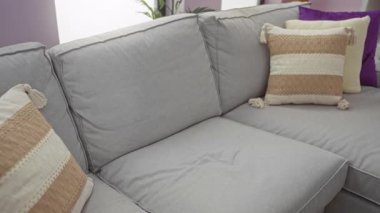 Sakallı genç adam şık bir oturma odasında akıllı telefon kullanarak rahat bir kanepede dinleniyor..