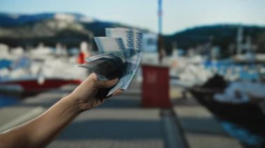 Elinde Macar banknotları tutan adam deniz kıyısında temiz gökyüzünün altında tekne ve su ile..