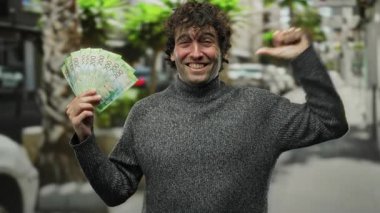 Palmiye ağaçlarıyla dolu bir şehir sokağında elinde Rus rublesi tutan İspanyol bir adam güvenini ve finansal başarısını ifade ediyor..