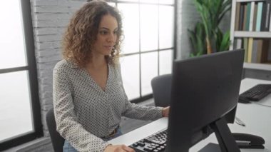 Modern ofiste bilgisayar başında çalışan kadın, doğal ışık ve minimalist tasarım ile profesyonel bir atmosferde ekrana odaklanıyor..