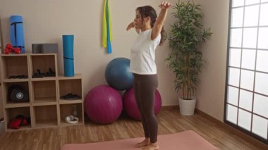 Spor salonunda yoga yapan bir kadın spor topları, iç mekan bitkileri ve spor ekipmanları ile dingin ve düzenli bir spor merkezinde sağlığın ve dengenin somutlaştırılması..