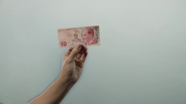 Duvarın arkasında el ele tutuşan Türk lirası banknotunda bir adamın para birimi ayrıntıları yer alıyor..