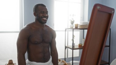 Kaplıcada havluyla gülümseyen yakışıklı Afro-Amerikalı adam.