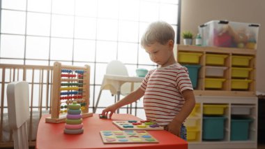Küçük çocuk, parlak bir anaokulu ortamında eğitici oyuncaklara konsantre oluyor, çocukluk eğitimi veriyor ve oyun oynuyor.