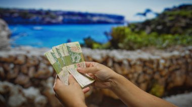 Adam, açık şehir ortamında güneşli bir deniz tatili için Hong Kong dolarları sayıyor. Yatırım ve para değişimi fırsatlarını resmediyor..