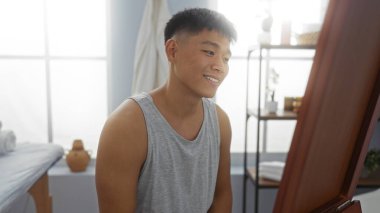 Kaplıcada gülümseyen yakışıklı genç bir Çinli. Yumuşak ışıklandırma ve modern dekorasyonla. İçerideki rahatlık ve sağlığın somutlaştırılmış hali.