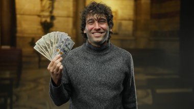 Kilise ortamında Amerikan dolarlarını elinde tutan İspanyol bir adam mutluluk ve tatmin ifadesiyle zenginlik ve maneviyat temalarını vurguluyor..