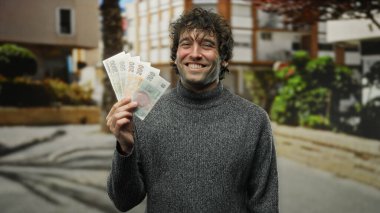 Czech Koruna banknotlarını elinde tutan İspanyol bir adam şehrin ortasında gülümsüyor..