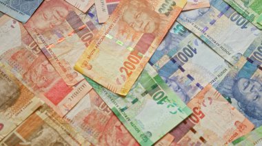 Mandela 'nın çeşitli Güney Afrika rand banknotları canlı renklerle dağınık bir düzende serilmiş, Güney Afrika' nın para biriminin çeşitli değerlerini vurguluyor..