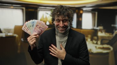 Samimi bir restoran ortamında Thai baht parasıyla gülümseyen bir adam mutluluk ve finansal başarı öneriyor..