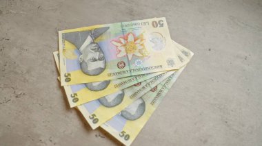 Somut bir yüzey üzerindeki 50 lelik banknotlarla Romen banknotları para birimi ayrıntıları ve mali temaları vurguluyor.