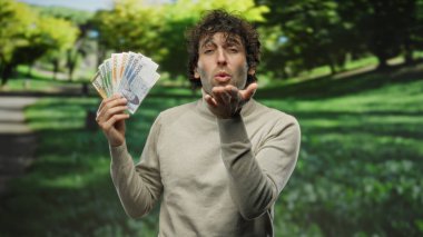 Güney Kore banknotlarını elinde tutan İspanyol bir adam kameraya bir öpücük yollarken neşeli ve neşeli bir sahne yakalıyor..