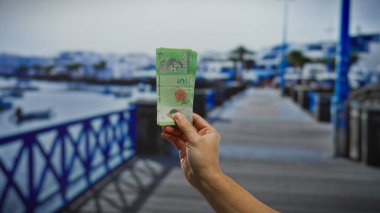 Deniz kıyısında el ele tutuşan Malezya ringgitleri, denizden teknelere binen adam, canlı yaz gezileri sahneleri..