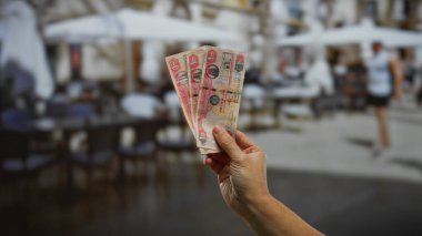 Sokak ticareti şehir yaşamını gösteren şehir kahvecisi terası önünde el ele tutuşan Dirham banknotları..