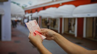 Kentsel bir sokak ortamında Tayvan doları tutan adam, hareketli bir şehir ortamında mali işlemleri ve açık havayı sembolize ediyor..