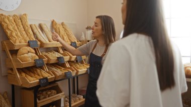 Fırıncı, fırının içindeki müşterilere çeşitli somun ve fiyat etiketleriyle ekmek seçeneklerini açıklıyor