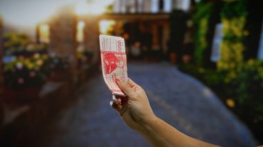 Şehir dışında güneşli bir sokakta elinde İzlanda Krona banknotu tutan bir adam. Şehir ortamında para ve yatırım kavramını gözler önüne seriyor..