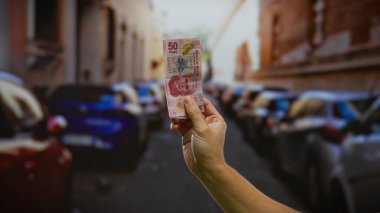 El ele tutuşarak Meksika pezosu şehir caddesinde arabaları park etmiş, şehir hayatının ve finans alışverişinin özünü yakalıyorlar..