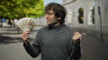 Elinde Rus rublesi tutan İspanyol bir adam şehir sokaklarında kararlı bir ifadeyle duruyor. Şehir manzarasında finans ve başarı temalarını vurguluyor..