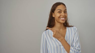 Genç bir kadın gülümsüyor ve izole edilmiş beyaz arka planı işaret ediyor.