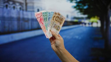 Şehirdeki bir sokak arkaplanında Çin Yuan banknotlarıyla el ele tutuşarak şehir merkezindeki iş finansmanını ön plana çıkarıyor..