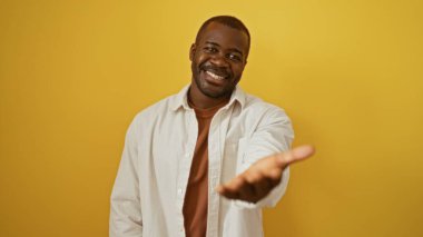 Genç, yakışıklı, siyah bir adam elini uzatıyor ve gülümsüyor.