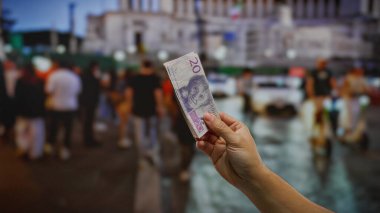 Kentsel caddede elinde İsviçre banknotları tutan bir adam arabalı ve arka plandaki insanlar açık bir şehir ortamında iş yatırımı öneriyor..