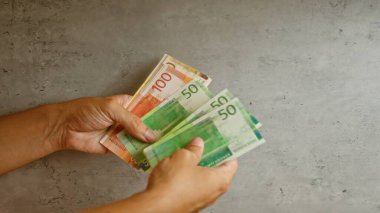 Elleri Norveçli kronları beton bir duvara dayayıp çeşitli değerleri gösteren banknotlar tutuyor