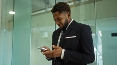 Ofisteki genç adam, kafası karışmış bir ifadeyle telefonuna bakıyor.