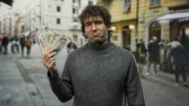 Banknotlara ve kentsel çevreye odaklanmış meşgul şehir caddesinde İngiliz sterlini tutan İspanyol bir adam.