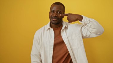 Genç adam burnuna neşeli bir ifadeyle canlı sarı bir arkaplan, özgüven ve karizmayı somutlaştıran.