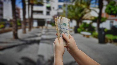 Peru tabanını elinde tutan bir kadın, kalabalık bir şehir ortamında para ve finansman sergiliyor..