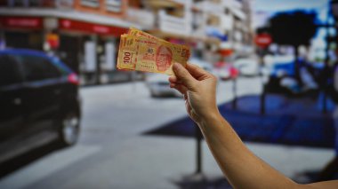 Kentsel bir sokak ortamında Meksika pesolarını tutmak, canlı bir şehir ortamında iş yatırımlarını ve finansal aktiviteleri temsil etmek, arabalar ve binalar görünür.