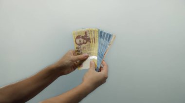 Elinde Macar forint banknotları tutan adam, beyaz bir arkaplan karşısında izole edilmiş, sergilenen para birimi işleme ve mali yönetim.