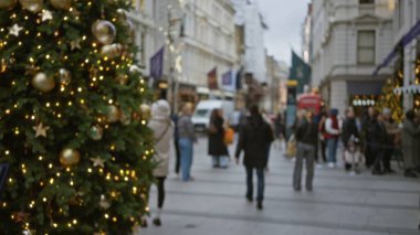 Londra 'da Noel süsleriyle süslenmiş bir sokak, kışın gökyüzünün altında yürüyen bulanık insanlar, ışıldayan ağaçlar, şenlikli, bokeh, odak dışı bir atmosfer yaratıyor..