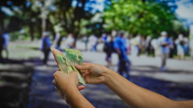 Adam, canlı bir şehir caddesinde, finans ve ekonomi odaklı canlı bir şehir ortamında iş ve para alışverişini harmanlayan Güney Afrika rand banknotlarına sahip..