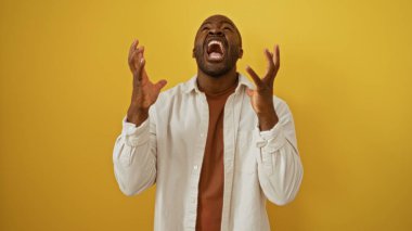 İzole edilmiş sarı bir arka planda duygusal bir ifadesi olan yakışıklı Afro-Amerikan erkeği.