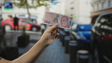 Şehir caddesinde el ele tutuşan Türk lirası banknotu, para değişimi ve ekonomiye odaklanarak hareketli kentsel ortamı yakalıyor.