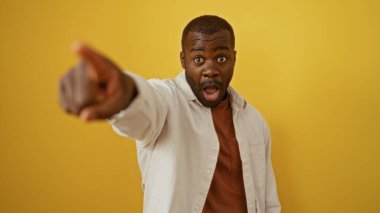 İzole edilmiş sarı bir arkaplan üzerinde anlamlı bir yüz gösteren genç adam, sürpriz ve heyecan taşıyor.