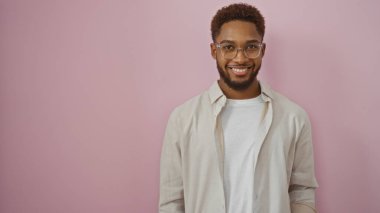 Soyutlanmış pembe arka planda gülümseyen yakışıklı genç bir adam.